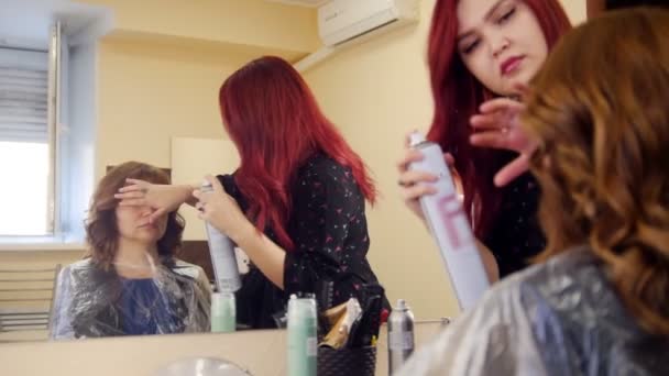 Жінка в косметологічній клініці. Спеціаліст з обприскування жіночого волосся за допомогою спрею для волосся — стокове відео
