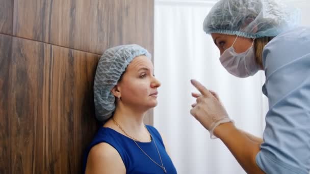 Vrouw in een kliniek cosmetologie. Specialist doen schetsen op dames gezicht — Stockvideo