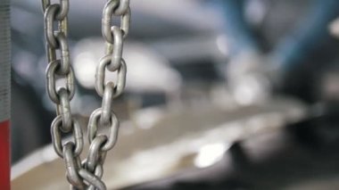 İşçinin bsckgrond zincirinde boya kaldırır ve öğütür ile kıvılcım bir detay arabanın ağır çekimde.
