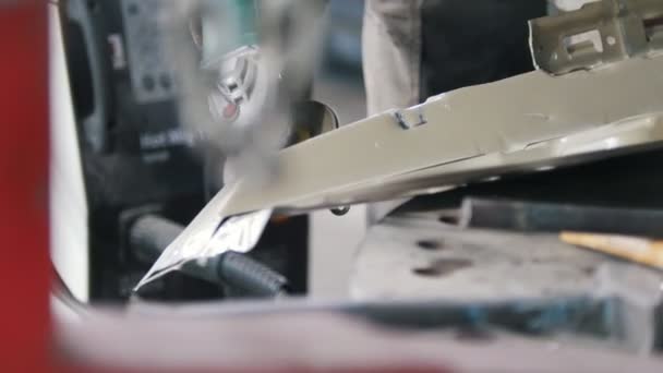 De arbeider verwijdert verf en maalt met sparks een detail van de auto in slow motion. Schuifregelaar schot — Stockvideo