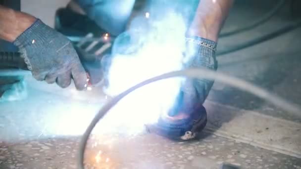 Hombre trabajador hace soldadura eléctrica en backgrond de chispas y humo — Vídeo de stock