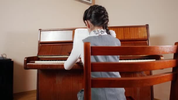 音乐课。女孩弹钢琴。从孩子的后背玩的滑块视图 — 图库视频影像