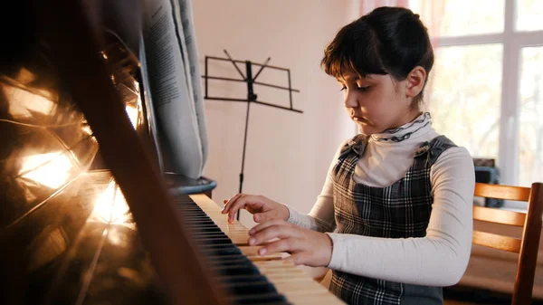 Une petite fille jouant du piano en cours de musique. Belle lumière du soleil — Photo