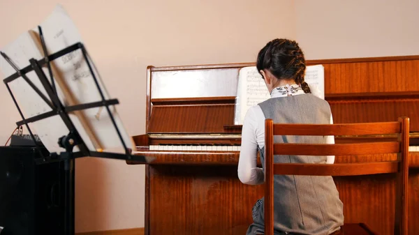 Una ragazzina che suona il pianoforte a lezione di musica. Vista posteriore . — Foto Stock