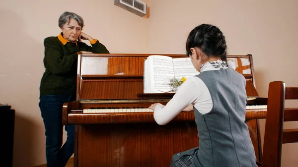Una ragazzina che suona il pianoforte a lezione di musica. Un insegnante che la guarda — Foto Stock