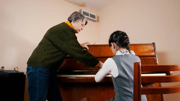 Egy kislány, zongorázni lecke zene. Segít neki, tanár — Stock Fotó