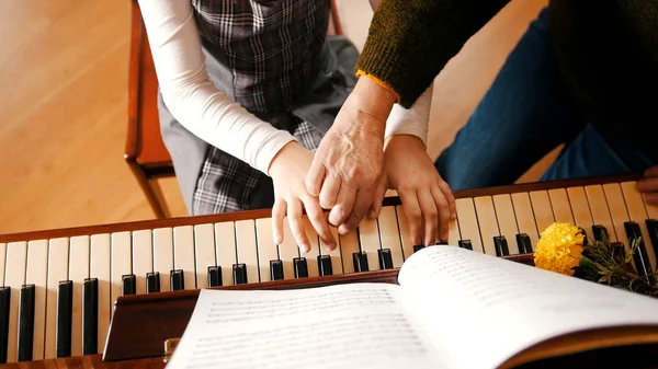 Una ragazzina che suona il pianoforte a lezione di musica. Un'insegnante che la aiuta. Mani — Foto Stock