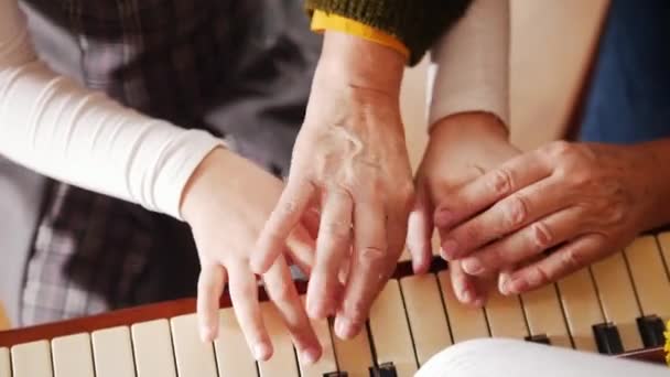 Lição musical. Menina tocando piano, professor mais velho fica perto dela e ajuda a tocar. Vista de cima — Vídeo de Stock