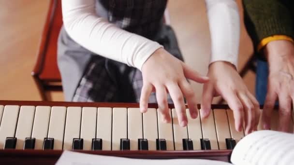 Lezione di musica. Ragazza che suona il pianoforte, anziano insegnante si siede vicino a lei e aiuta con la riproduzione. Vista dall'alto — Video Stock