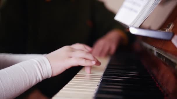 Lição musical. Menina tocando piano, professor mais velho senta-se perto e ajuda a tocar. Vista do lado direito — Vídeo de Stock