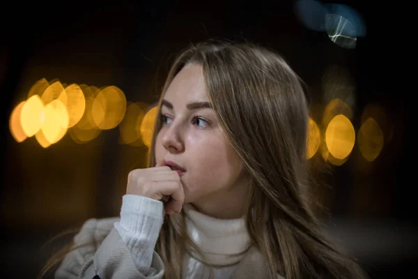 Portrait of young woman in the subway waiting for the train. Looking to the side. Back lights.