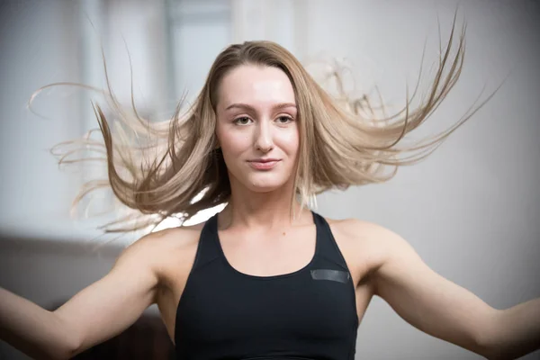 Joven mujer atractiva en sujetador deportivo en el estudio de entrenamiento. Cabello volador —  Fotos de Stock