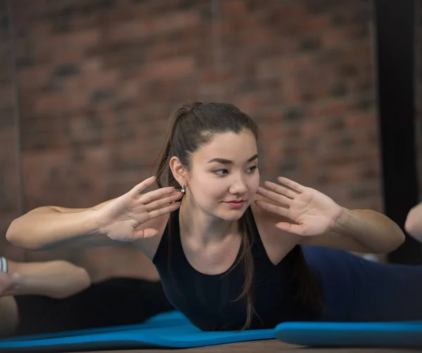 Pole Dance Studio, Gruppe von Frauen, die Stretching machen, sich auf dem Bauch drehen, auf Backsteinmauern. Wellness und gesunder Lebensstil. — Stockfoto