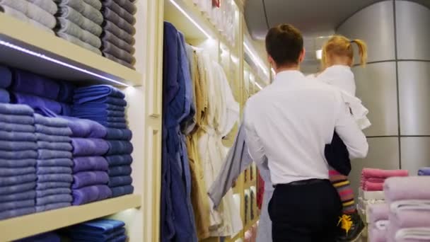 Een familie op winkelen. Een familie wandelen in het winkelcentrum op zoek naar de badjassen — Stockvideo