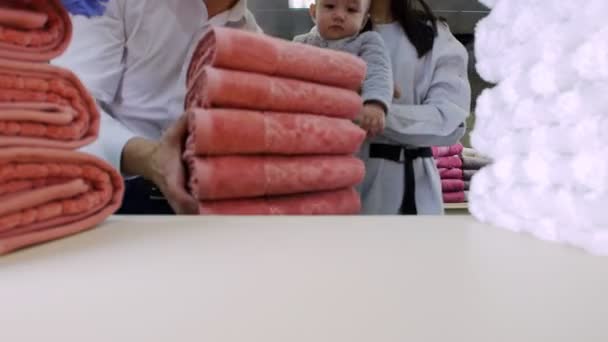 Uma família em compras. Um homem a tirar uma pilha de toalhas, família a olhar para a câmara — Vídeo de Stock
