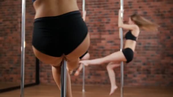 Kvinna tränare visar hur man pole dance. Flickor som snurrar runt stången — Stockvideo