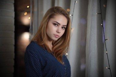 Güzel genç kadın portresi ışıklar içinde geçmiş üzerinden kameraya bakarak sarı saçlı başını yana eğdi.