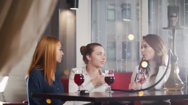 Három fiatal nő ül a vízipipa hely, dohányzás — Stock videók