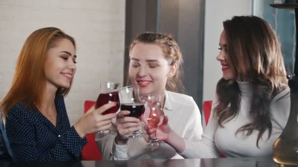 Tři mladé ženy sedící v místě vodní dýmka, pití. Na zdraví a polibky na tvář svého přítele — Stock video