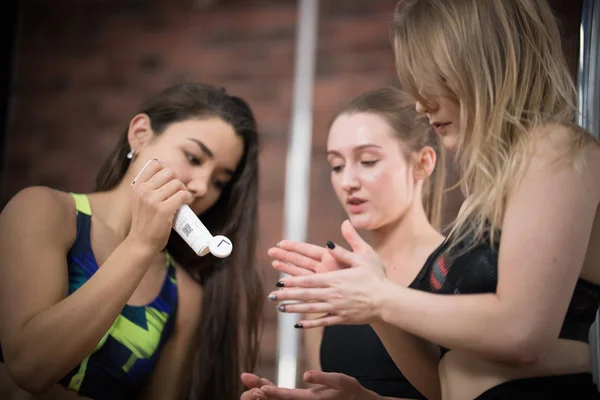 Tre unga kvinna i sport bh smörjer dansare händer med grädde — Stockfoto