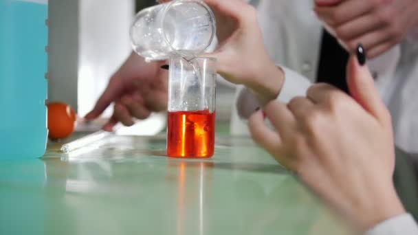 Хімічна лабораторія. Молода жінка робить експеримент, змішуючи рідини, шукаючи реакцію — стокове відео