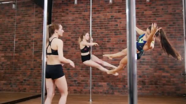 Zwei Frauen, die eine Pose in einem Pole-Fitness-Kurs mit Instruktor üben. Dynamischer Mast — Stockvideo