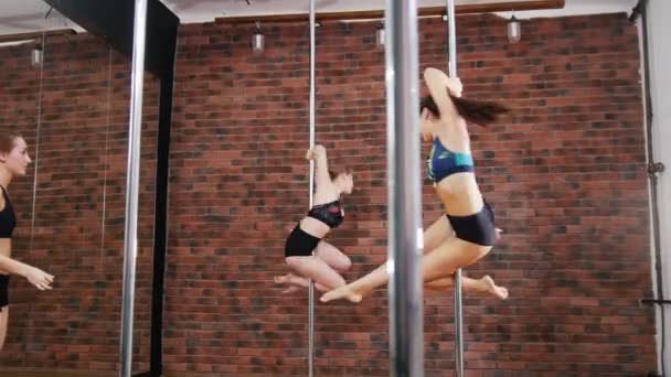 Två kvinnor som tränar en pose i en pole fitness klass. Dynamiska pylon — Stockvideo