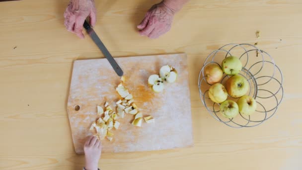 En gammal kvinna skära äpple. En liten flicka som tar en bit — Stockvideo