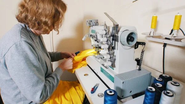 Alfaiate fêmea trabalhando com máquina de costura na fábrica — Fotografia de Stock