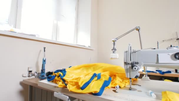 Mature woman puts a batch of t-shirts next to the sewing machine — Stock Video