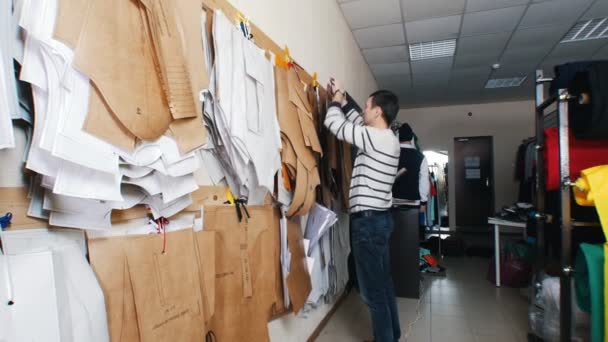 Fábrica de ropa. Un hombre tomando plantillas de la pared . — Vídeos de Stock