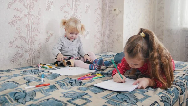 Due bambine sdraiate sul letto a disegnare — Foto Stock