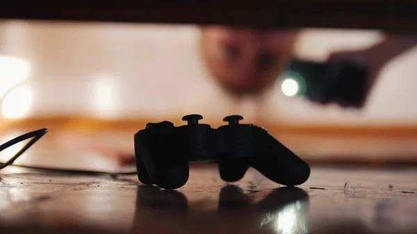 Schwarzer Joystick unter dem Bett. Mädchen schaut unter das Bett — Stockfoto