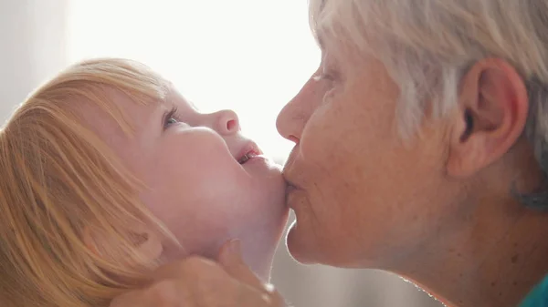 Портрет бабушки и внучки. Бабушка целует внучку — стоковое фото
