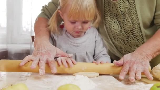 Сім'я робить маленькі пироги. Маленька дівчинка викидає тісто з допомогою — стокове відео
