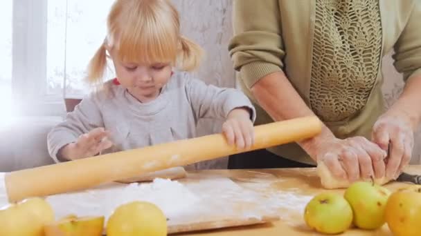 Familia haciendo pastelitos. Una niña pequeña saca la pasta — Vídeos de Stock