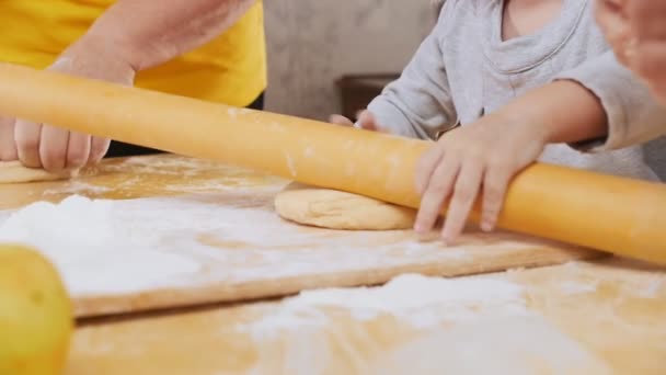 Family making little pies. A little girl rolls out the dough with grandmother help. Slow motion — Stock Video