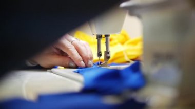 Kadın kumaş dikiş makinesi üzerinde çalışıyor. Kumaş üzerinde odaklanmak