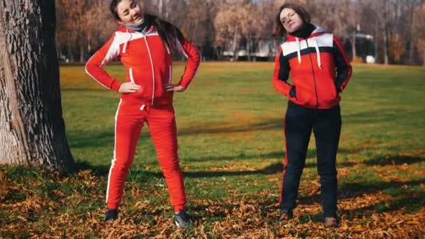 Two young woman in sport costumes are starting warming up in park — Stock Video