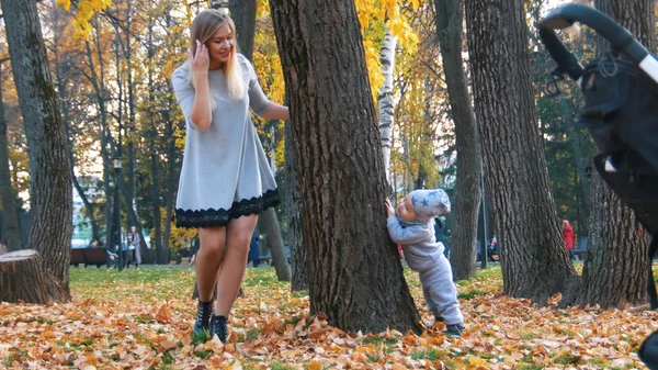 Молодая мать и ее маленький ребенок в парке. Игра в прятки — стоковое фото
