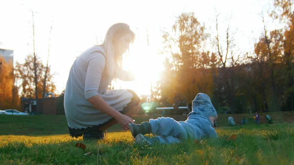 Mladá maminka a její miminko hraje v parku. S úsměvem — Stock fotografie