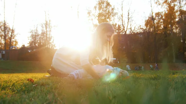 Mladá maminka a její miminko hraje v parku. Krásné sluneční světlo — Stock fotografie
