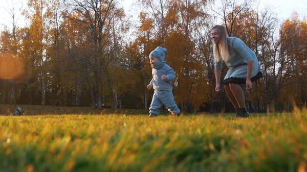 Ung mamma och hennes lilla bebis som spelar i höstens park — Stockfoto