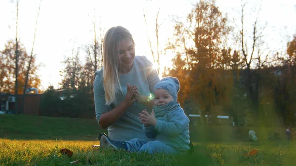 Joven madre y su pequeño bebé jugando en el parque de otoño, sonriendo — Foto de Stock