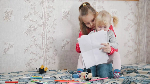 Két kaukázusi kislány ül az ágyon, és a rajz — Stock Fotó