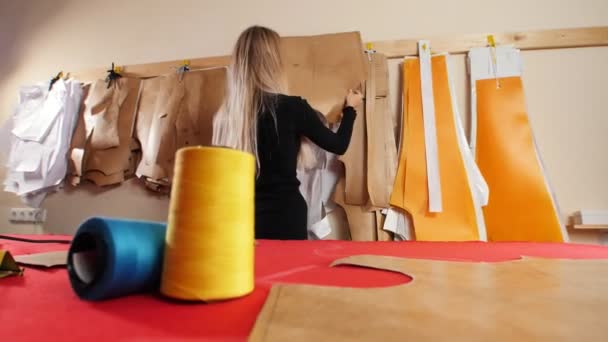 缝纫厂的年轻女子。一个女人从墙上拿模板. — 图库视频影像