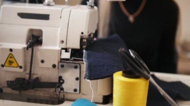 Dikiş makinesi ile fabrika üzerinde çalışan genç kadın. Makinenin arkasında