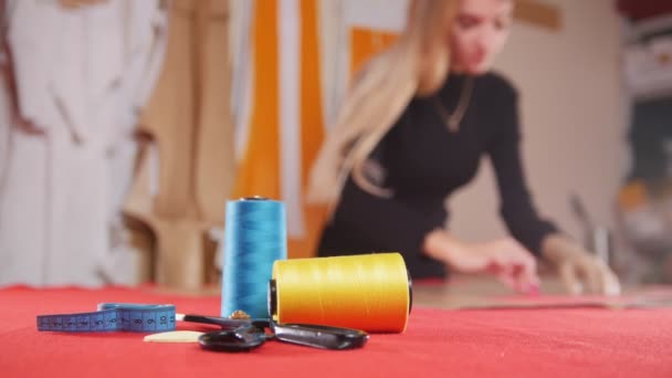 布の上のスケッチを作る縫製工場で若い女性。フォーカスのミシン糸。静的なショット — ストック動画
