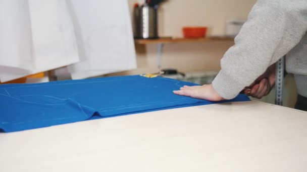 Arbeiter in der Bekleidungsfabrik legt säuberlich ein blaues Tuch auf den Tisch — Stockvideo
