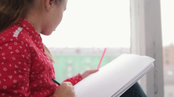 A girl sitting on the windowsill and drawing something. Close up — Stock Video